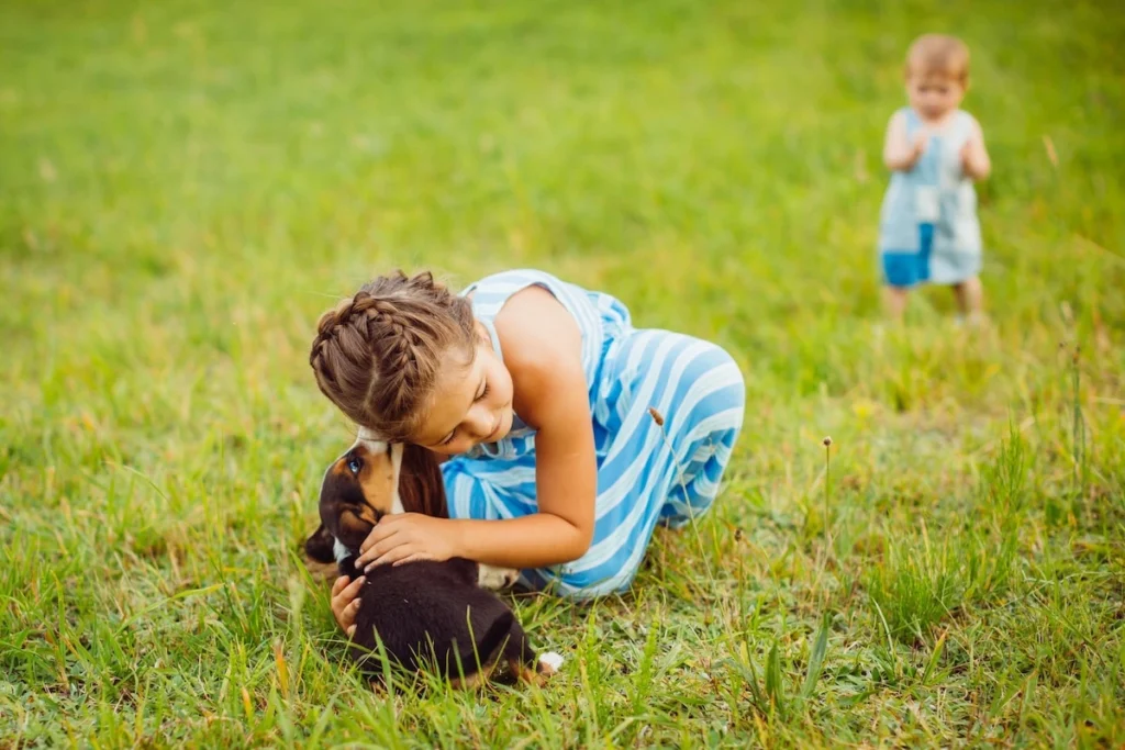 Happy girl cuddles puppy outdoors with reliable recurring pet waste cleanup provider